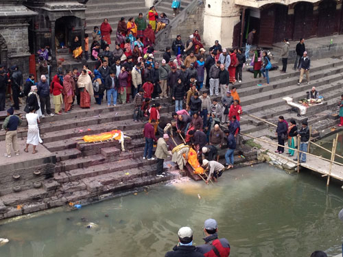 Family members washing the body of a deceased loved on with chai, before setting the body on fire.